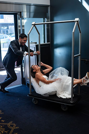Groom pushes bride on a bell cart