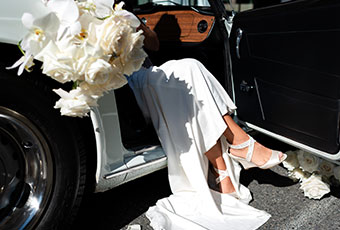 Close up of brides dress and shoes as she sits in car with door open
