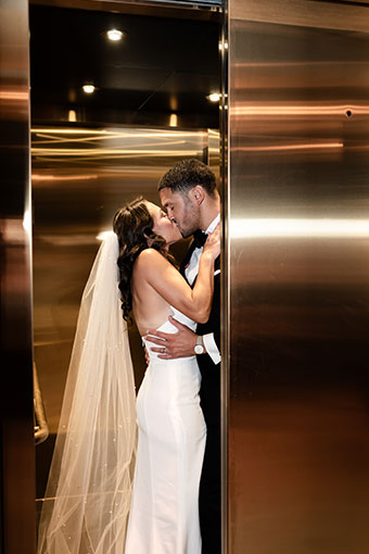 Bride and groom kiss as elevator door closes